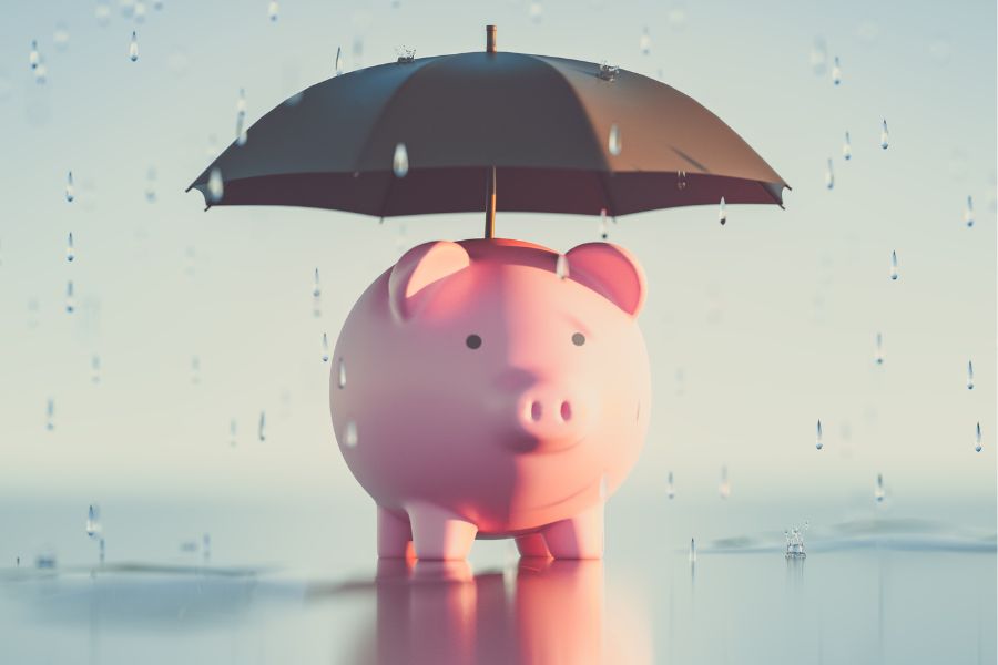 A piggy bank with an umbrella on top of it, covering it from the rain
