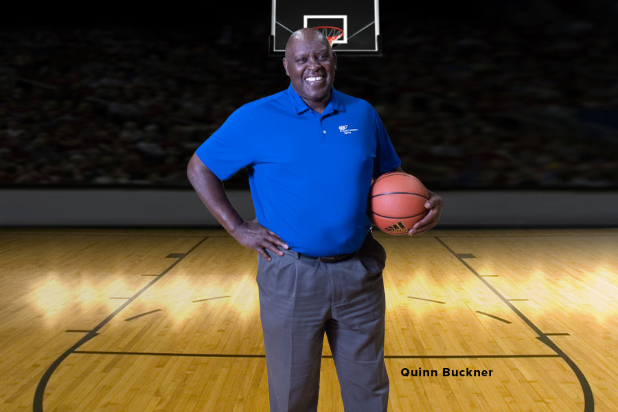 Quinn Bucker former professional basketball player and coach, in a blue AAA shirt, standing basket ball court