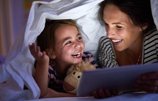 Peace of Mind happy family, mother and daughter reading under blanket covers