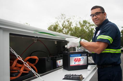 Mobile automotive battery service technician holding a AAA battery