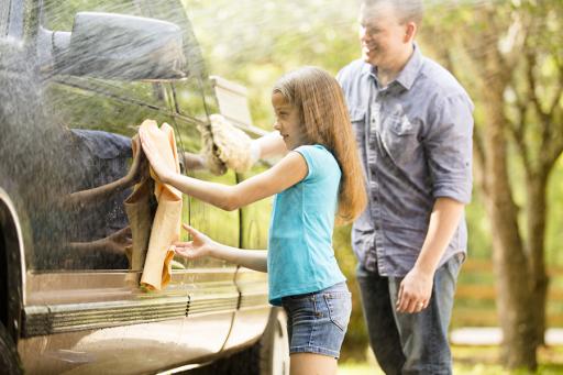 Insurance, father and daughter outside washing a black truck