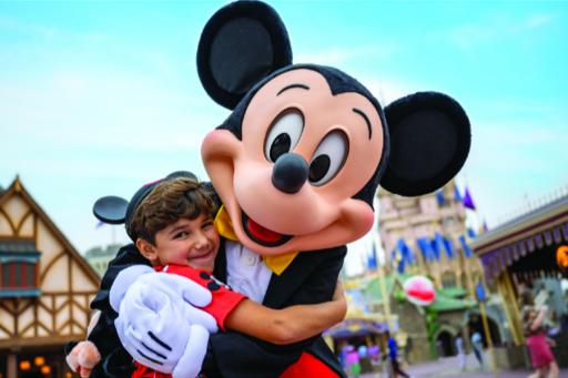MIckey Mouse hugging a child with Mickey ears